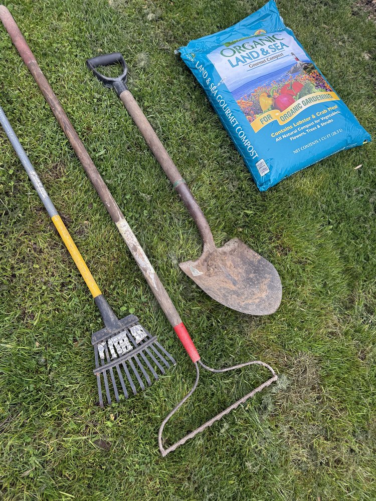 Planting tools laid out on the grass — shovel, rakes, and Dr. Earth Organic Landscaper's Mix