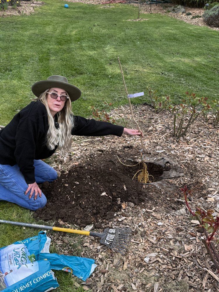 Carol laughing next to the newly planted tree
